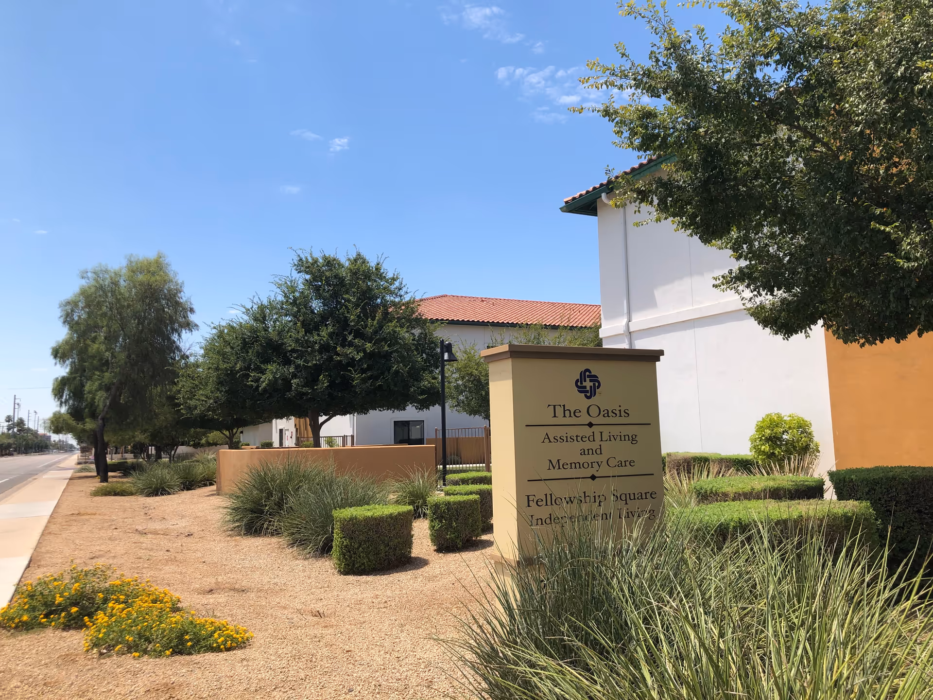 Exterior view of The Oasis at Fellowship Square sign amid desert landscaping in Mesa