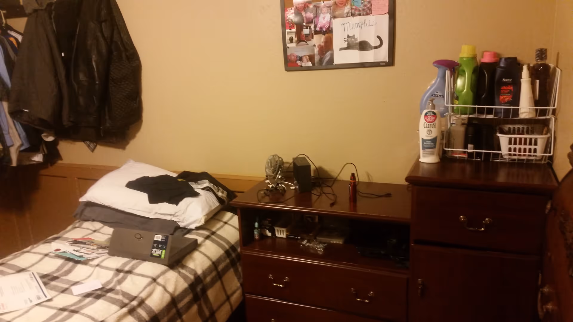 A cluttered bedroom featuring a bed, dresser, and scattered personal items.