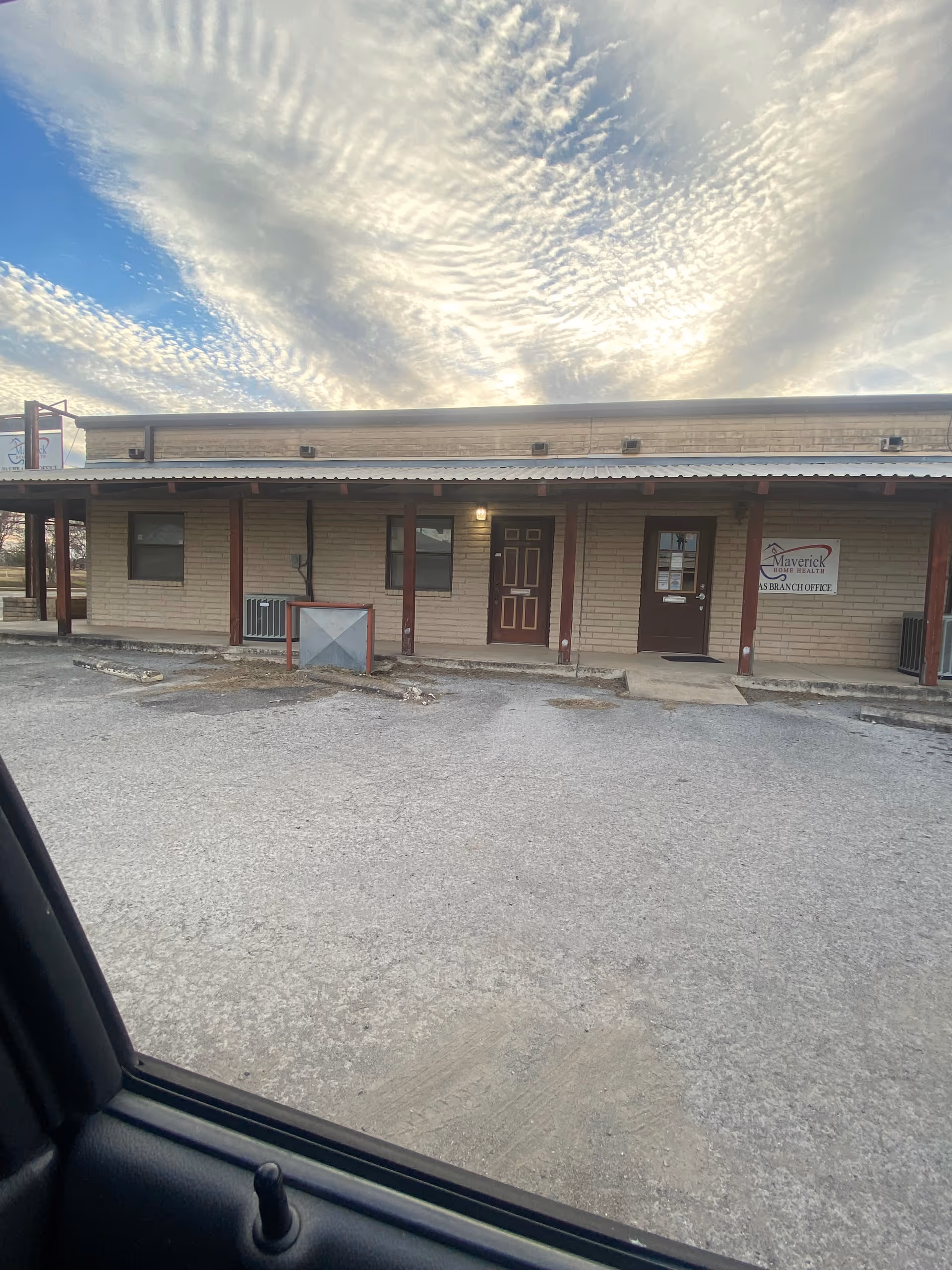 Single-story beige facility with Maverick Home Health Agency sign, two doors, and a parking lot.