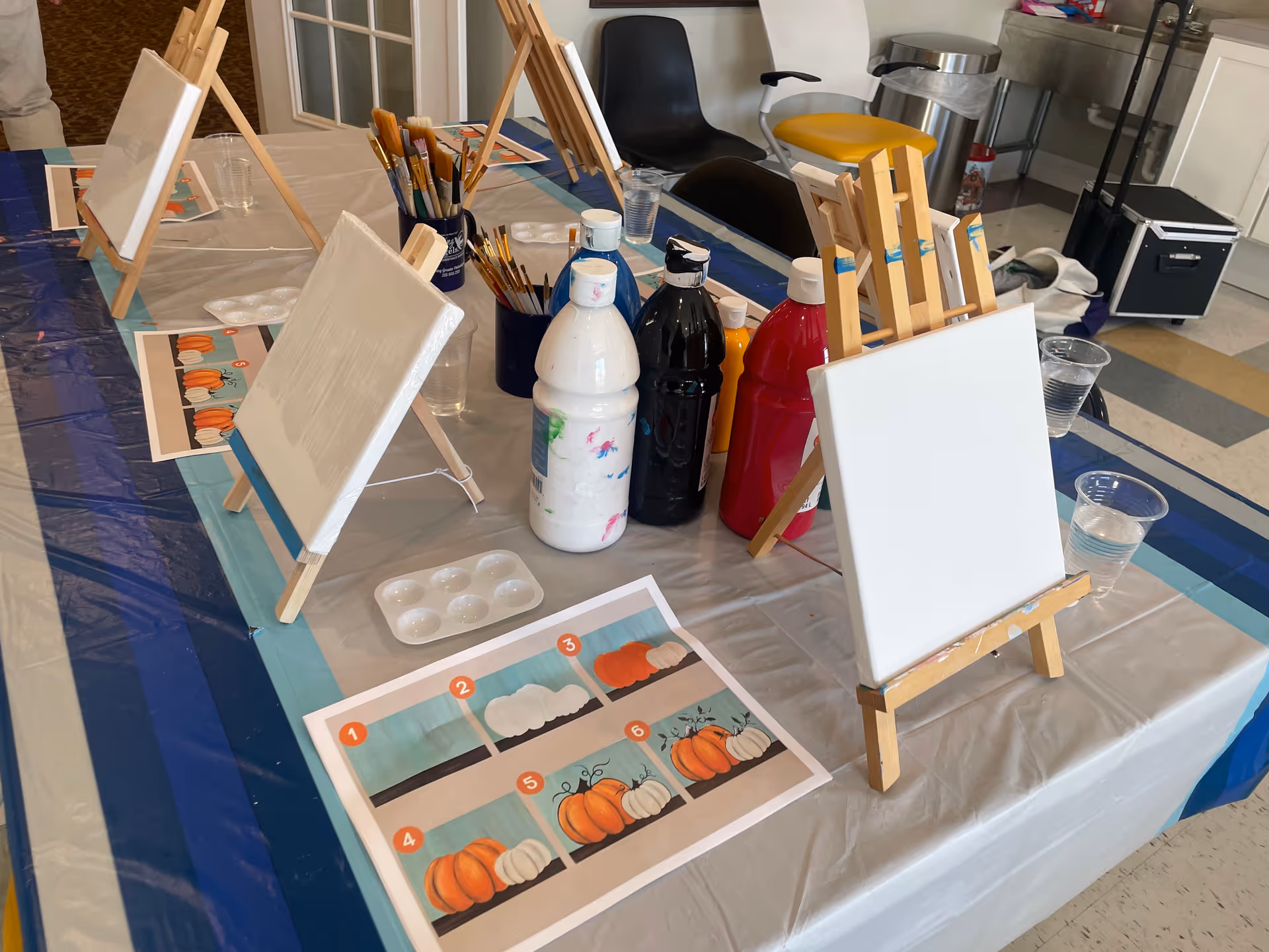 Art activity table with easels, paints, and brushes in a senior home care facility.