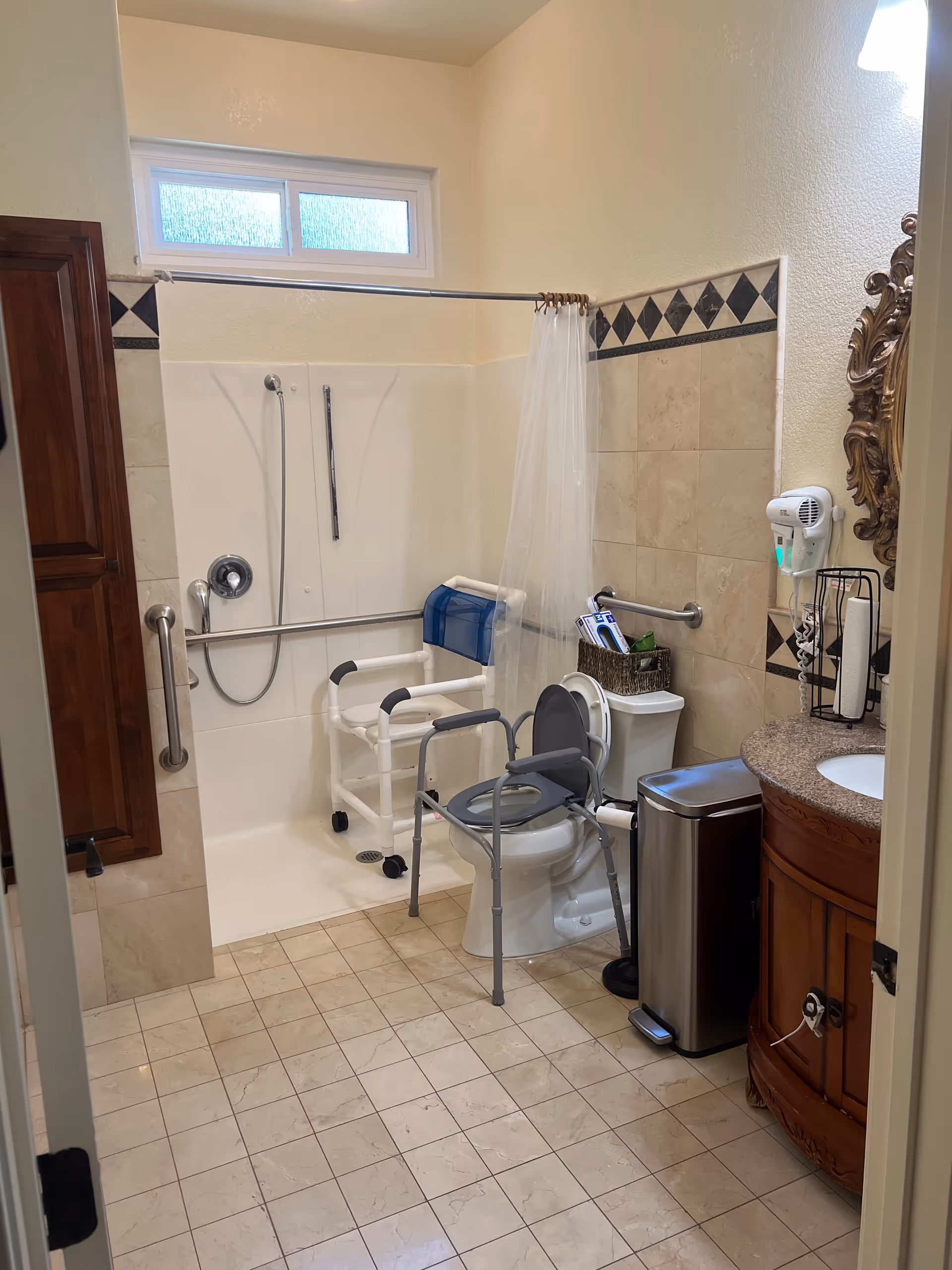 Accessible bathroom with shower, toilet, grab bars, walker, and sink in senior facility.