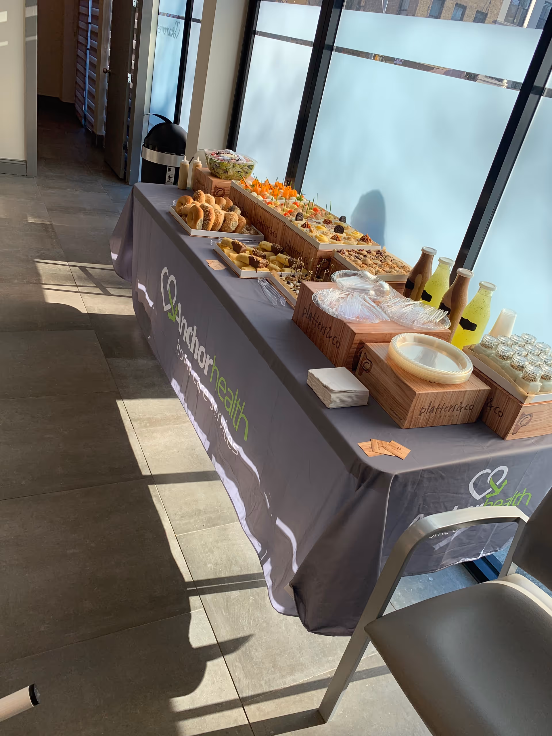 Refreshment table with pastries and drinks in a bright indoor corridor branded Anchor Health.