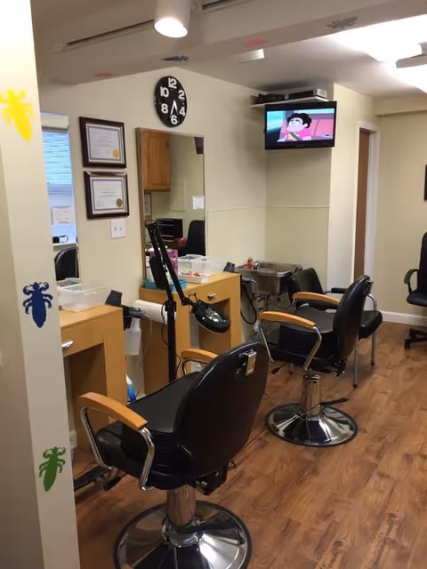 Salon area inside a senior living facility with barber chairs, mirrors, and a TV.