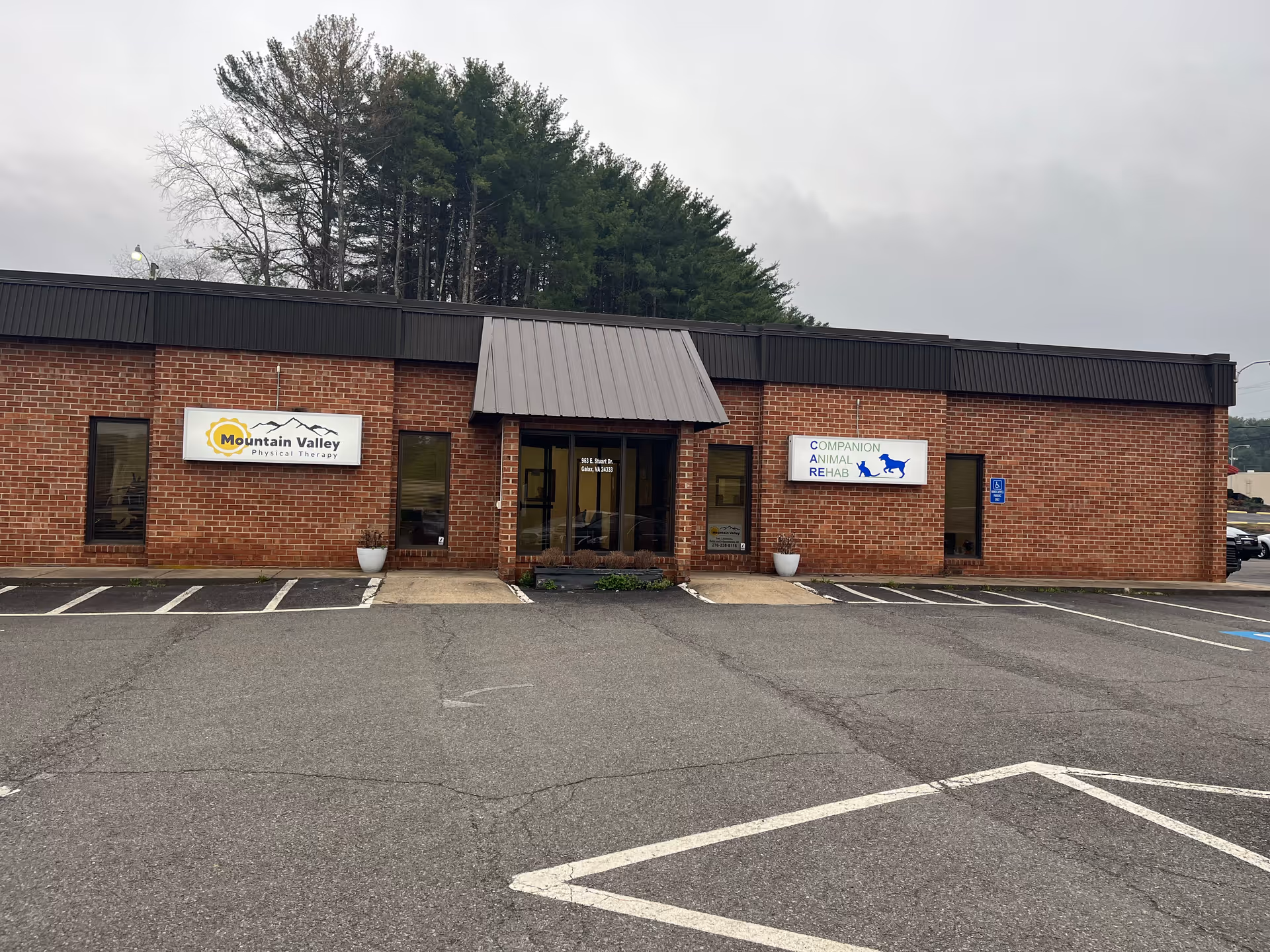 Brick one-story building with Mountain Valley Physical Therapy and Companion Animal Rehab signs in a lot.