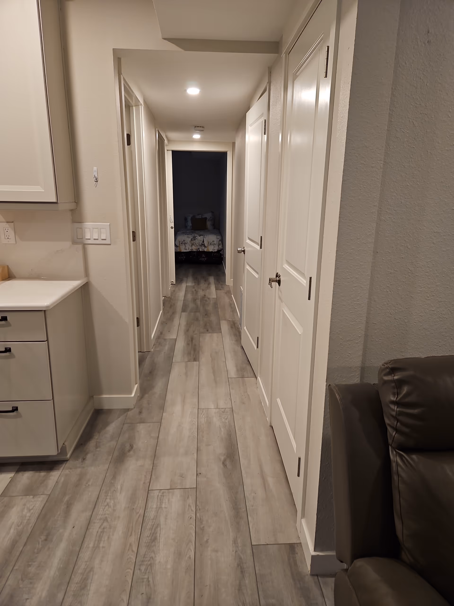 Long hallway in a senior living facility with a bedroom visible at the far end.