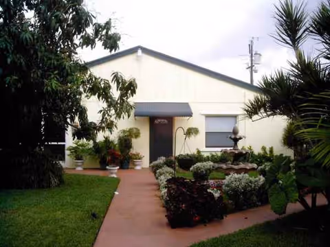 Front view of a single story assisted living building with a landscaped garden path and entryway.