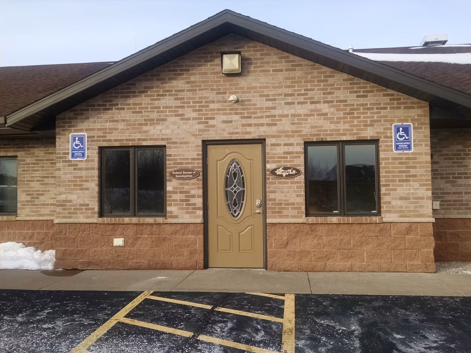Brick building front with central door and wheelchair-accessible signs.
