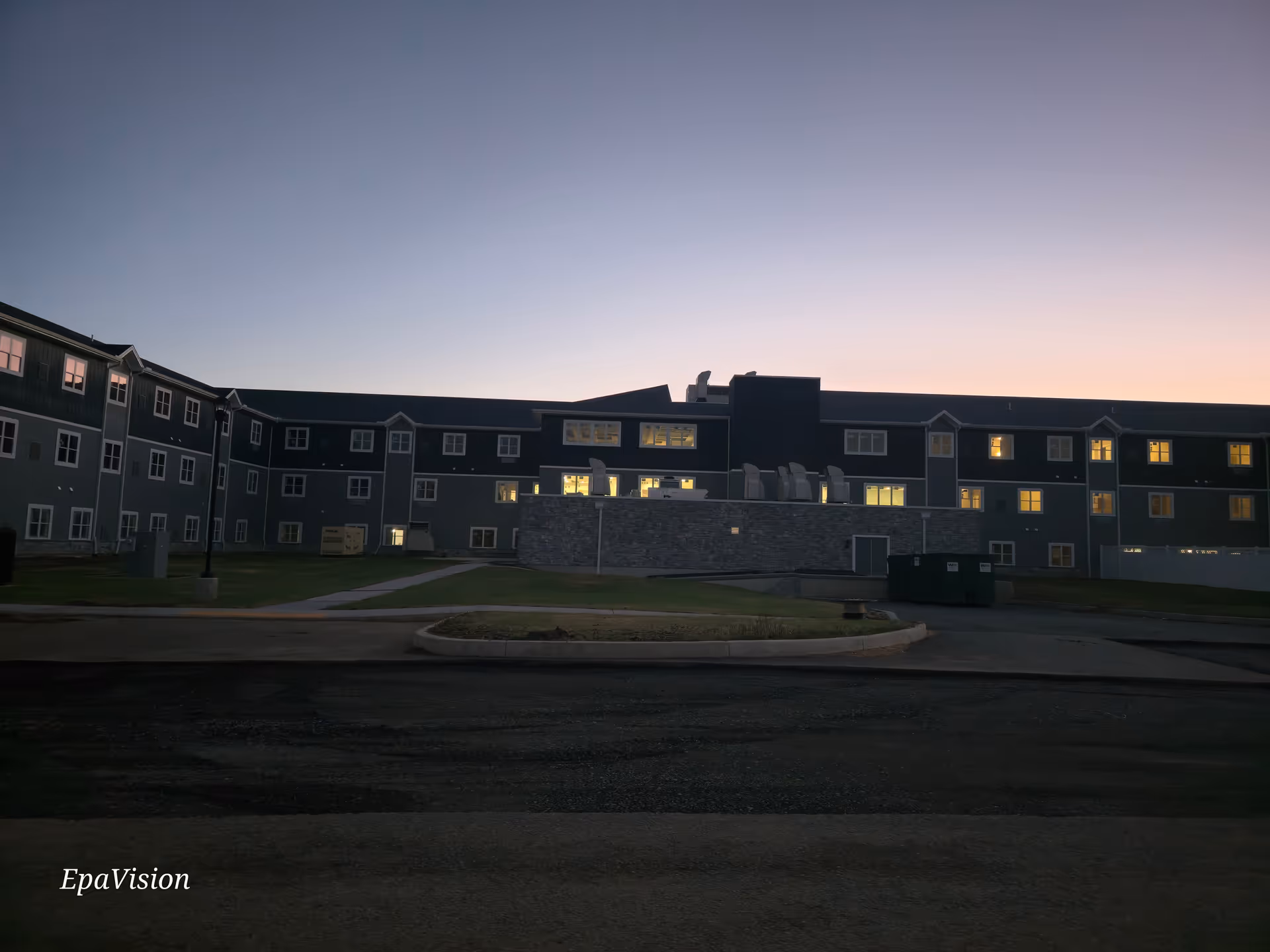 Exterior view of The Residence at Boyertown building at dusk with lit windows.