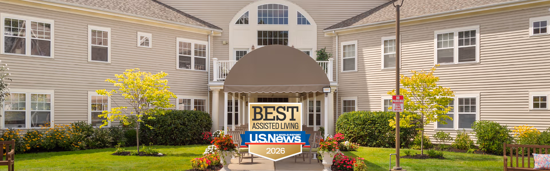 Exterior view of Benchmark at Orchard Valley building entrance with Best Assisted Living sign.