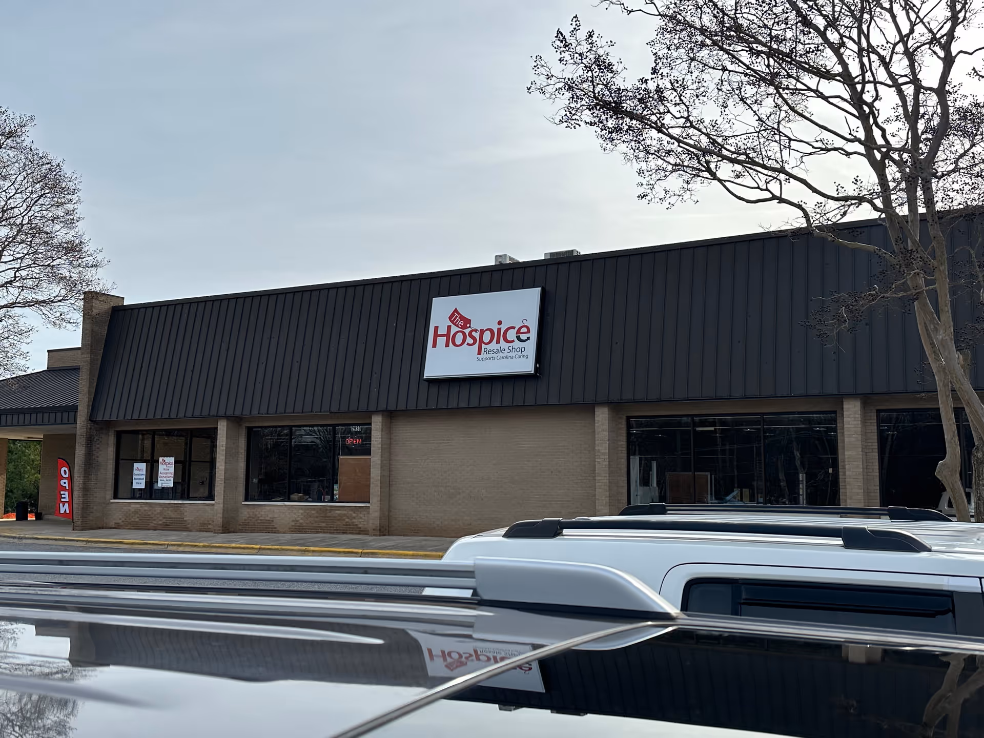 Exterior view of a hospice storefront with a large sign and parked vehicles.