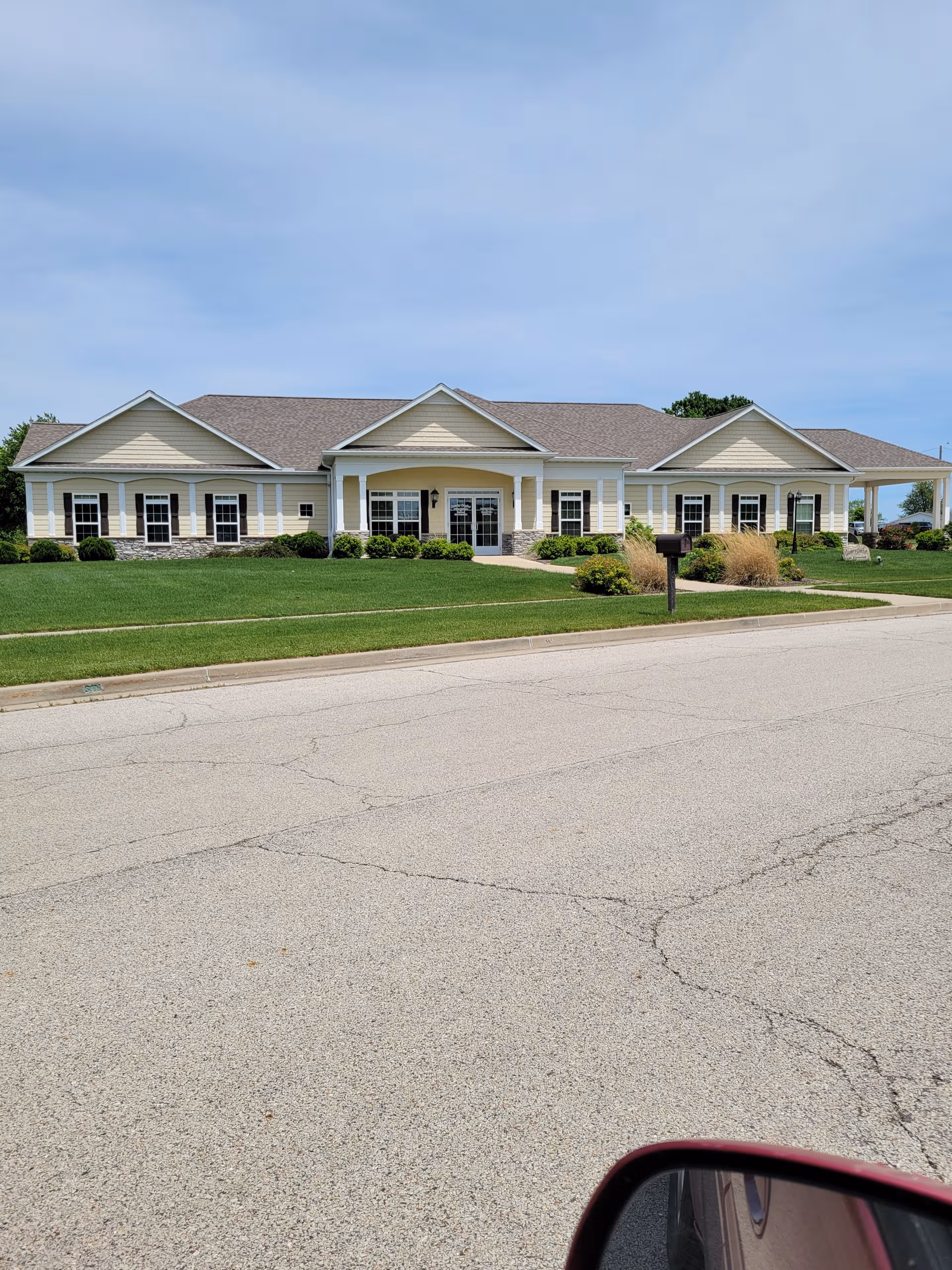 Single-story retirement home exterior with a green lawn and driveway.