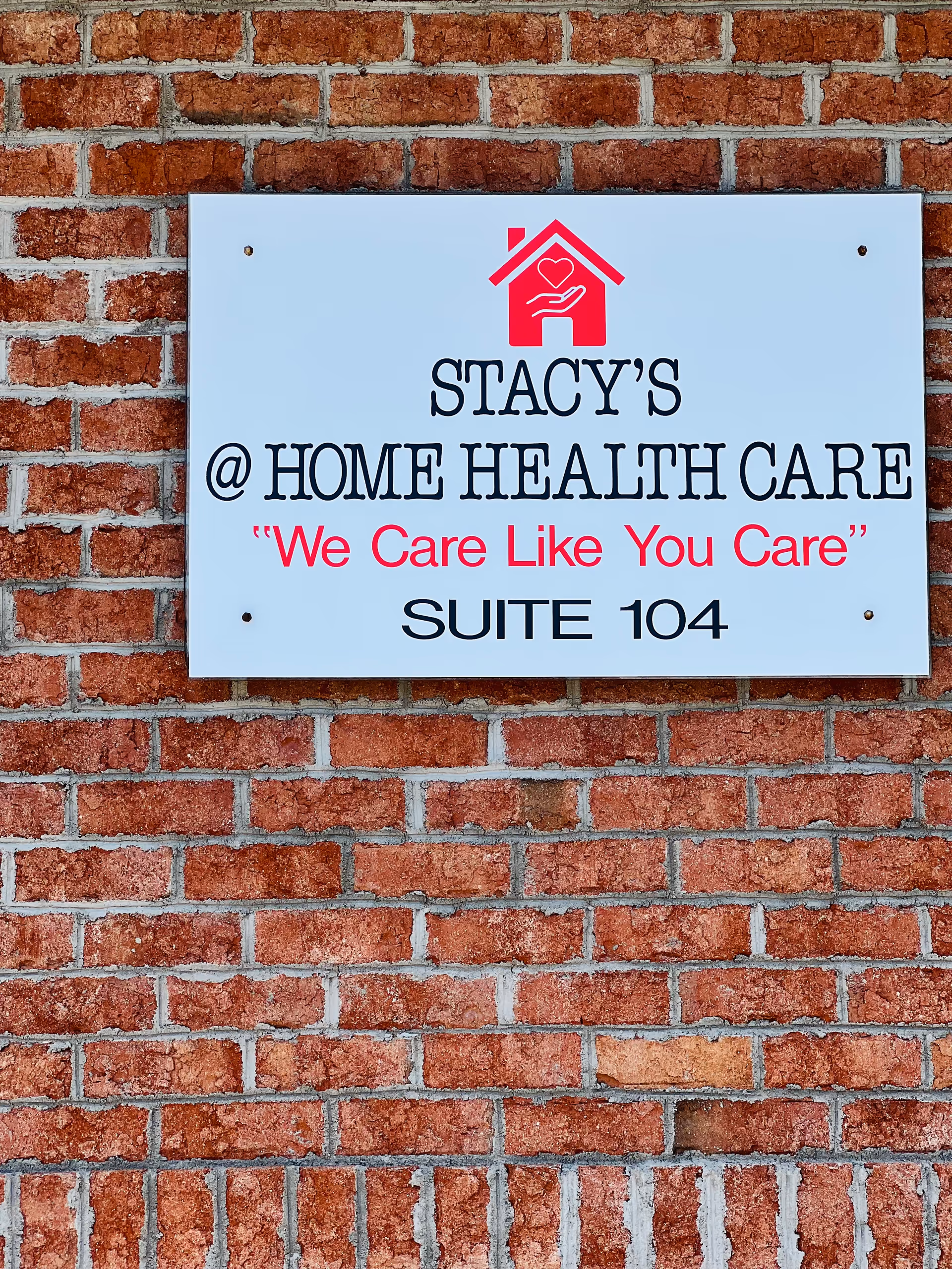 Sign on brick wall reading Stacy's @ Home Health Care, Suite 104.