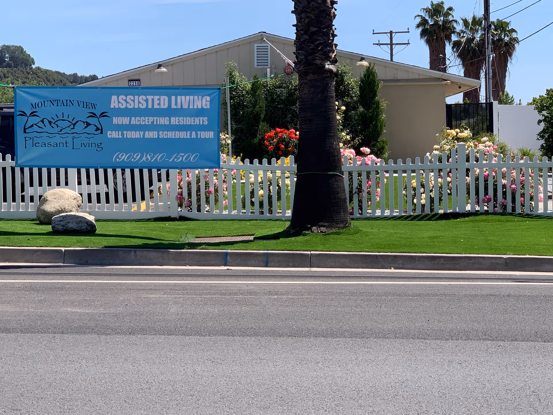 Front view of Mountain View Assisted Living with a blue banner and white picket fence.