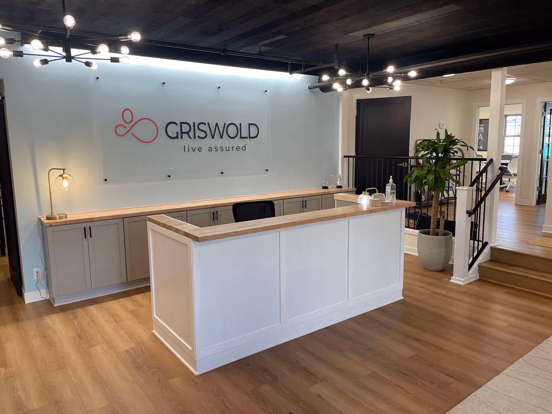Reception desk in a modern lobby with Griswold sign and a potted plant.