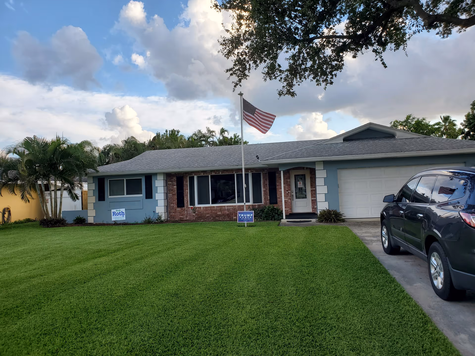Avalon Luxury Living facility exterior with flagpole, manicured lawn, and parked SUV.
