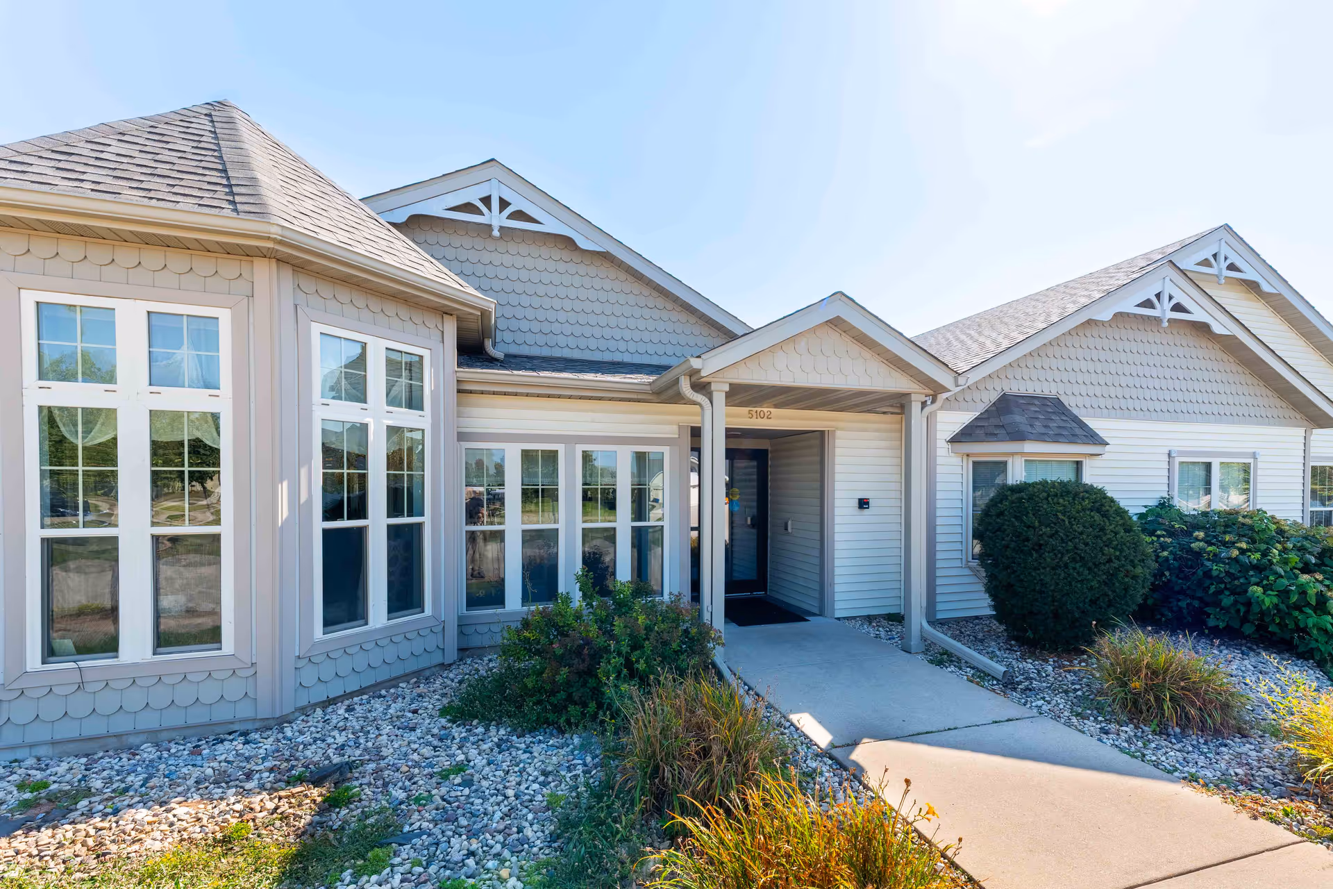 Front view of Apple Creek Place exterior with entrance path and large windows.