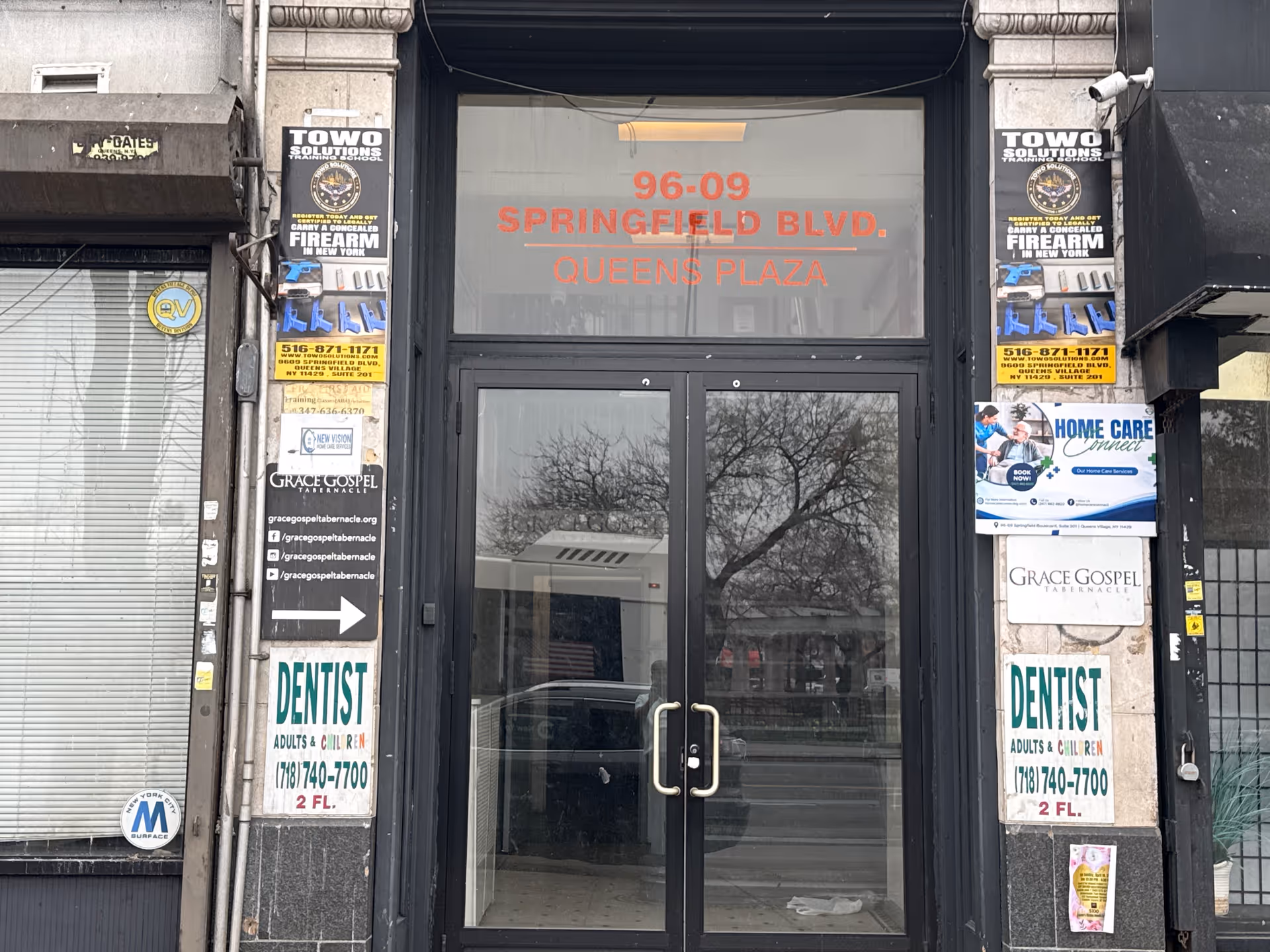 Front entrance of a building with glass doors and multiple storefront signs.