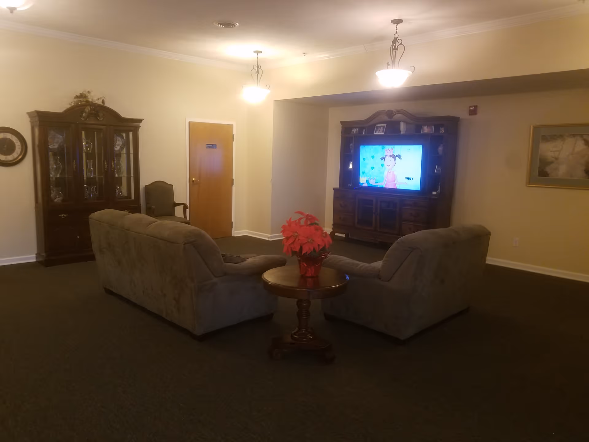 Cozy senior living lounge with two upholstered sofas, a coffee table, and a TV.