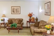 A cozy living room with patterned sofas, tables, lamps, and wall art.
