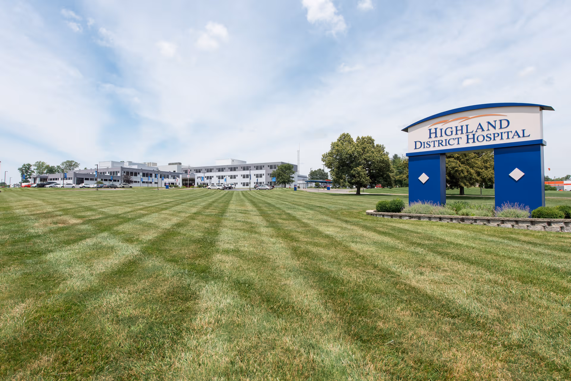 Exterior view of Highland District Hospital with a large grassy lawn and sign.