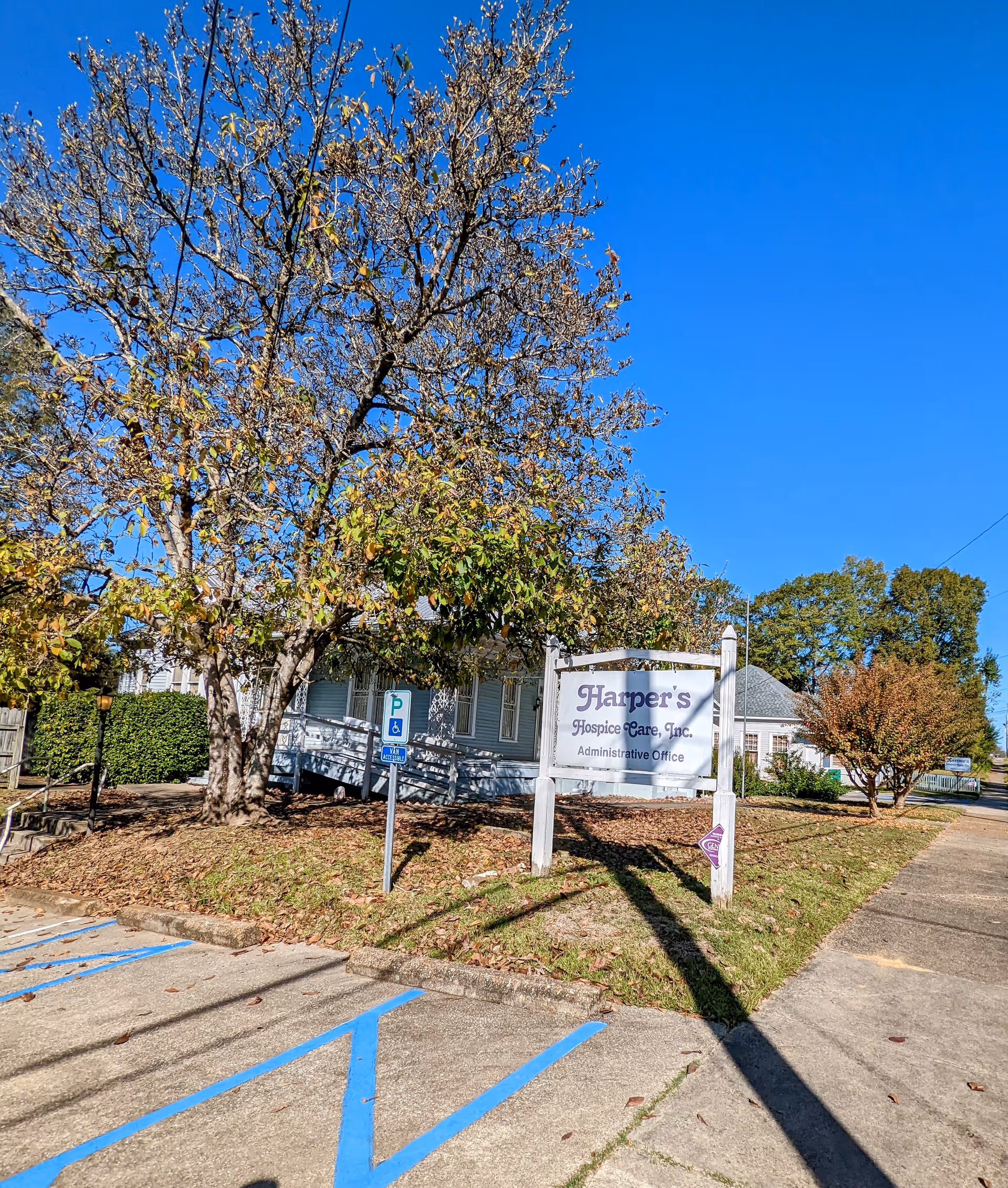 Exterior view of Harper's Hospice Care, Inc administrative office with sign, trees, and parking