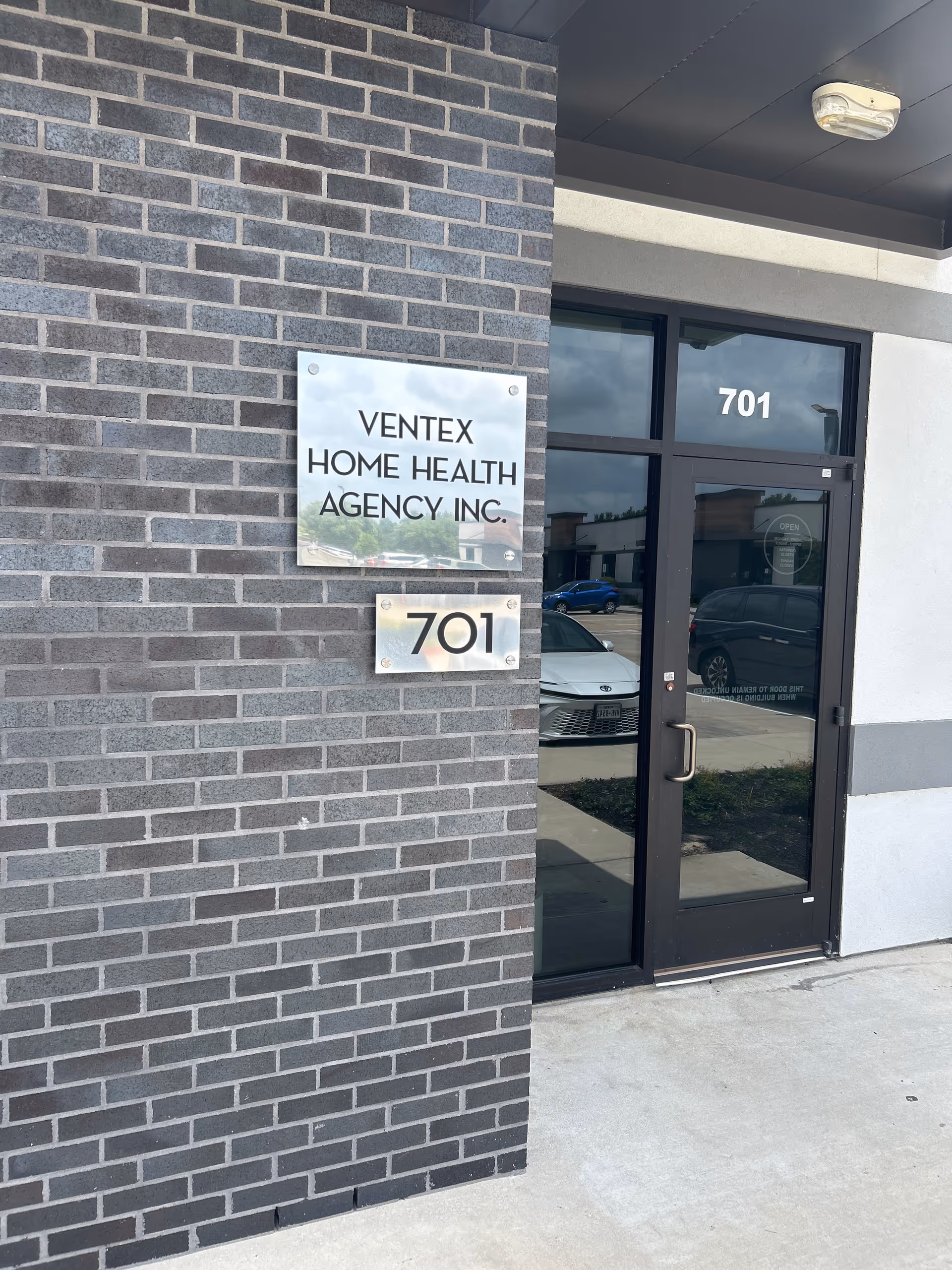 Exterior view of Ventex Home Health Agency entrance with brick wall and glass door.