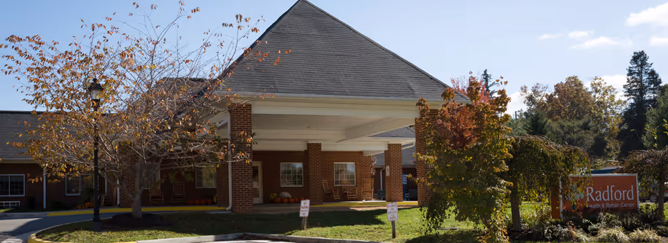 Brick senior living center entrance with trees, awning, and a Radford Health and Rehab sign.