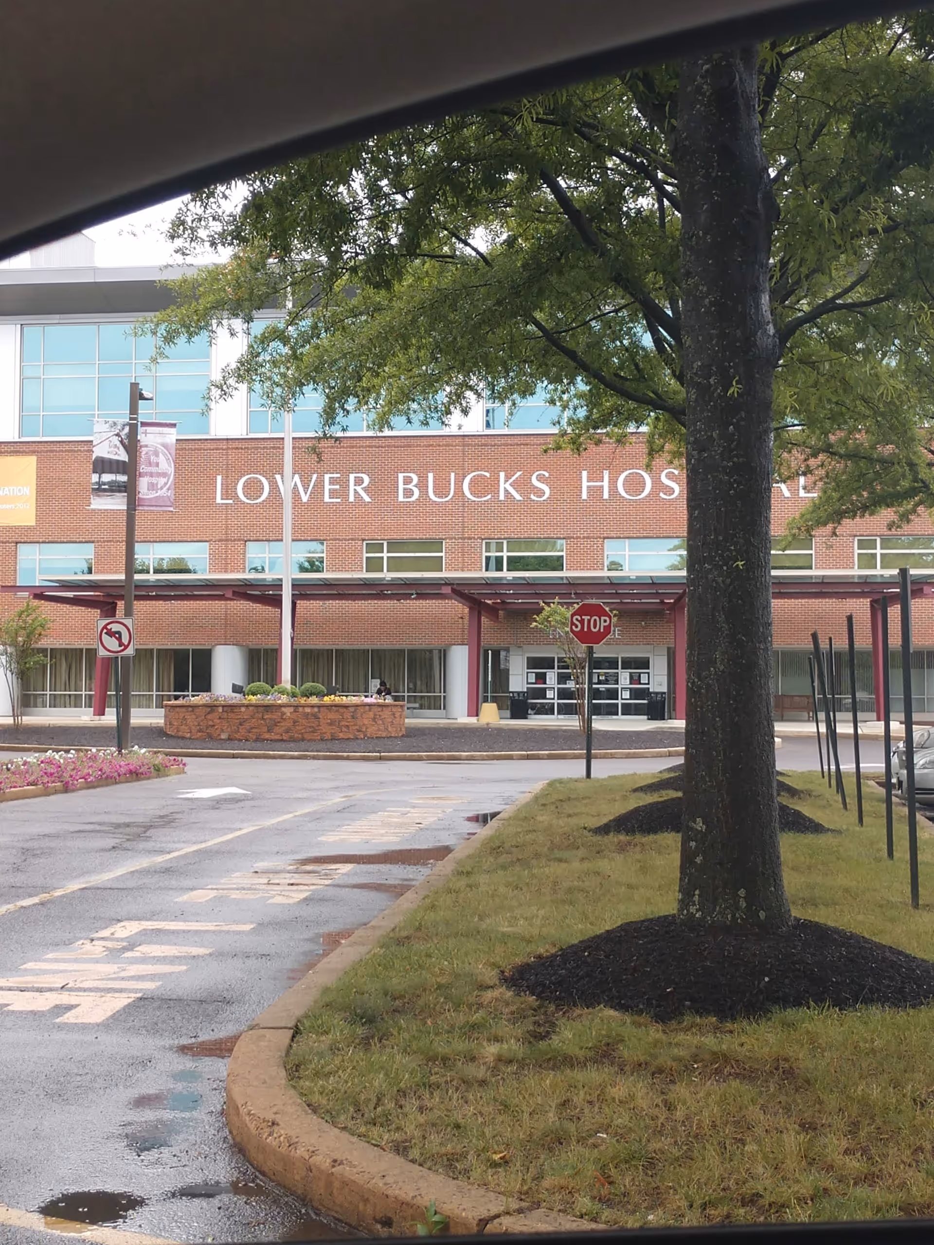 Exterior view of Lower Bucks Hospital entrance with brick facade and surrounding trees.