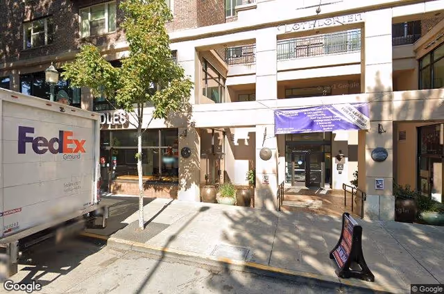 Exterior view of a building entrance with a FedEx truck parked on the street.