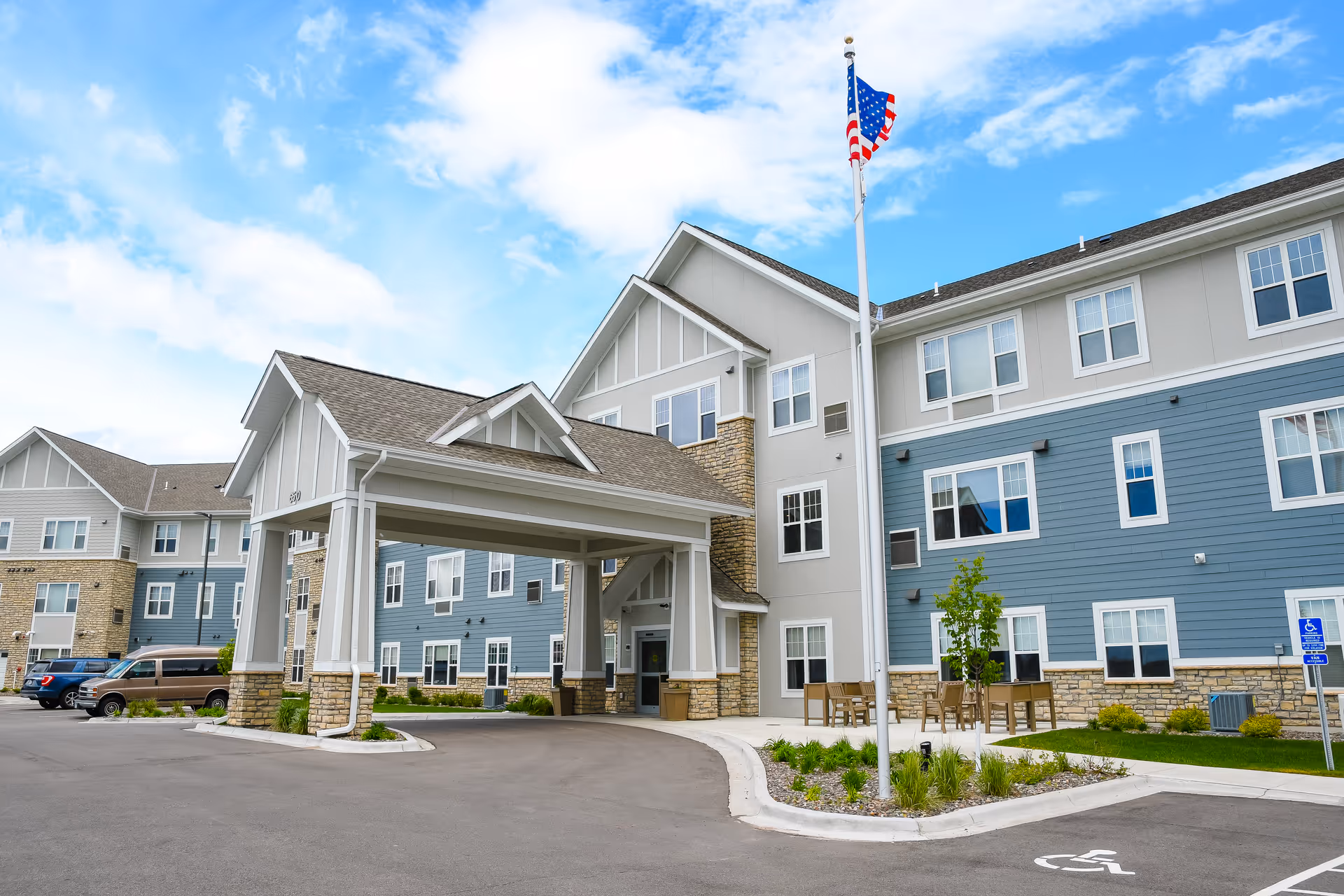 Exterior view of Timber Pines by Vivie senior living, featuring entrance canopy and flagpole.