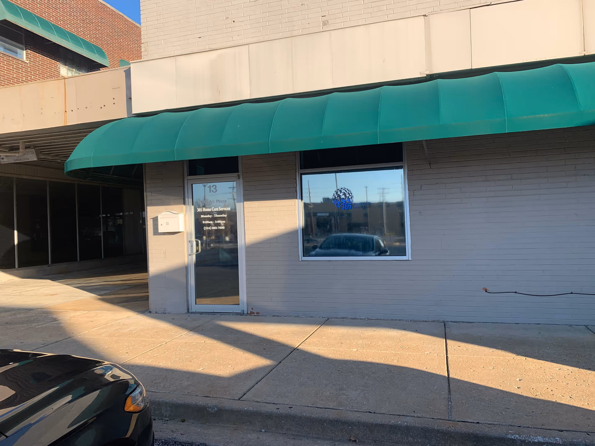Exterior view of a building front with a green canopy and glass door.
