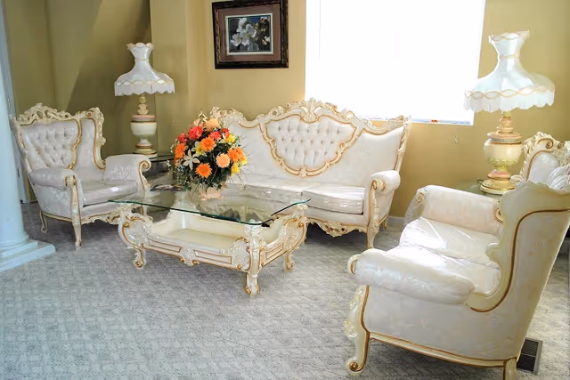 Elegant vintage living room with cream upholstered furniture, glass coffee table, and flowers.