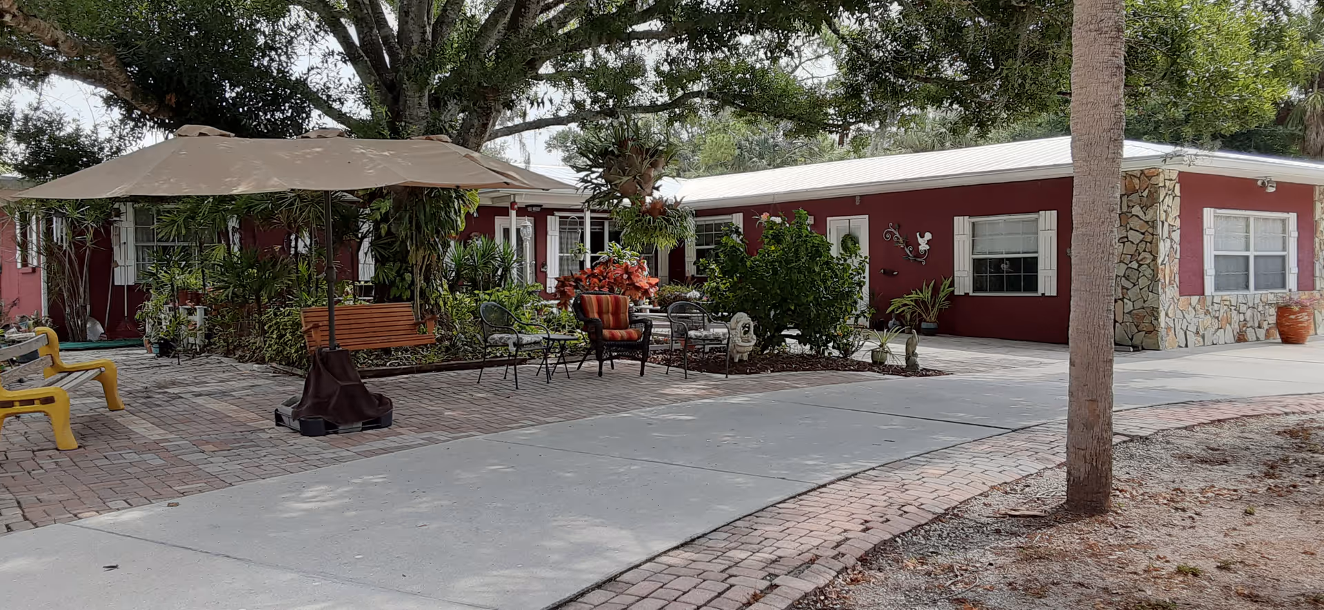 Outdoor patio area with a red building, umbrella, and assorted seating.