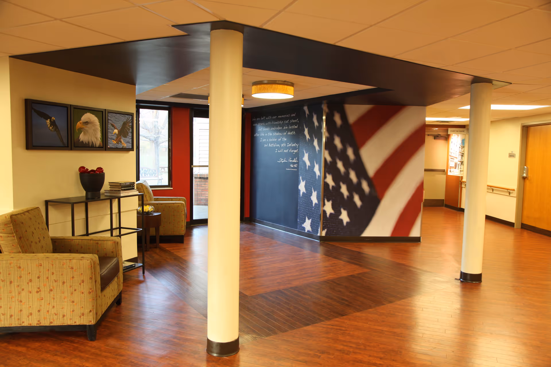 Comfortable lobby area with beige armchairs, pillars, and an American flag mural along the wall.