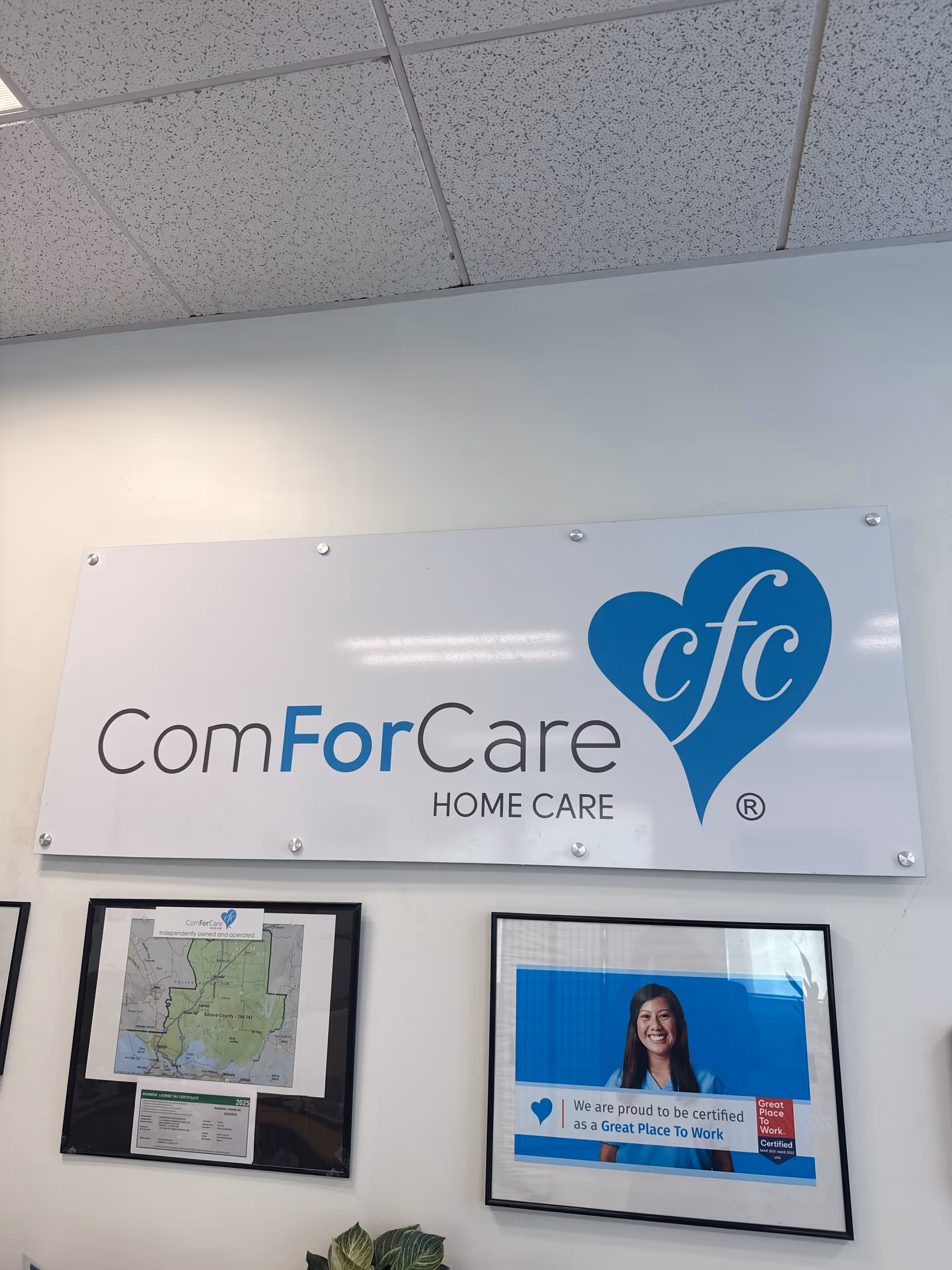Indoor wall with ComForCare Home Care sign and framed photos.
