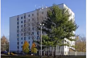 Tall white Wind Pine Senior Living building with trees and blue sky.