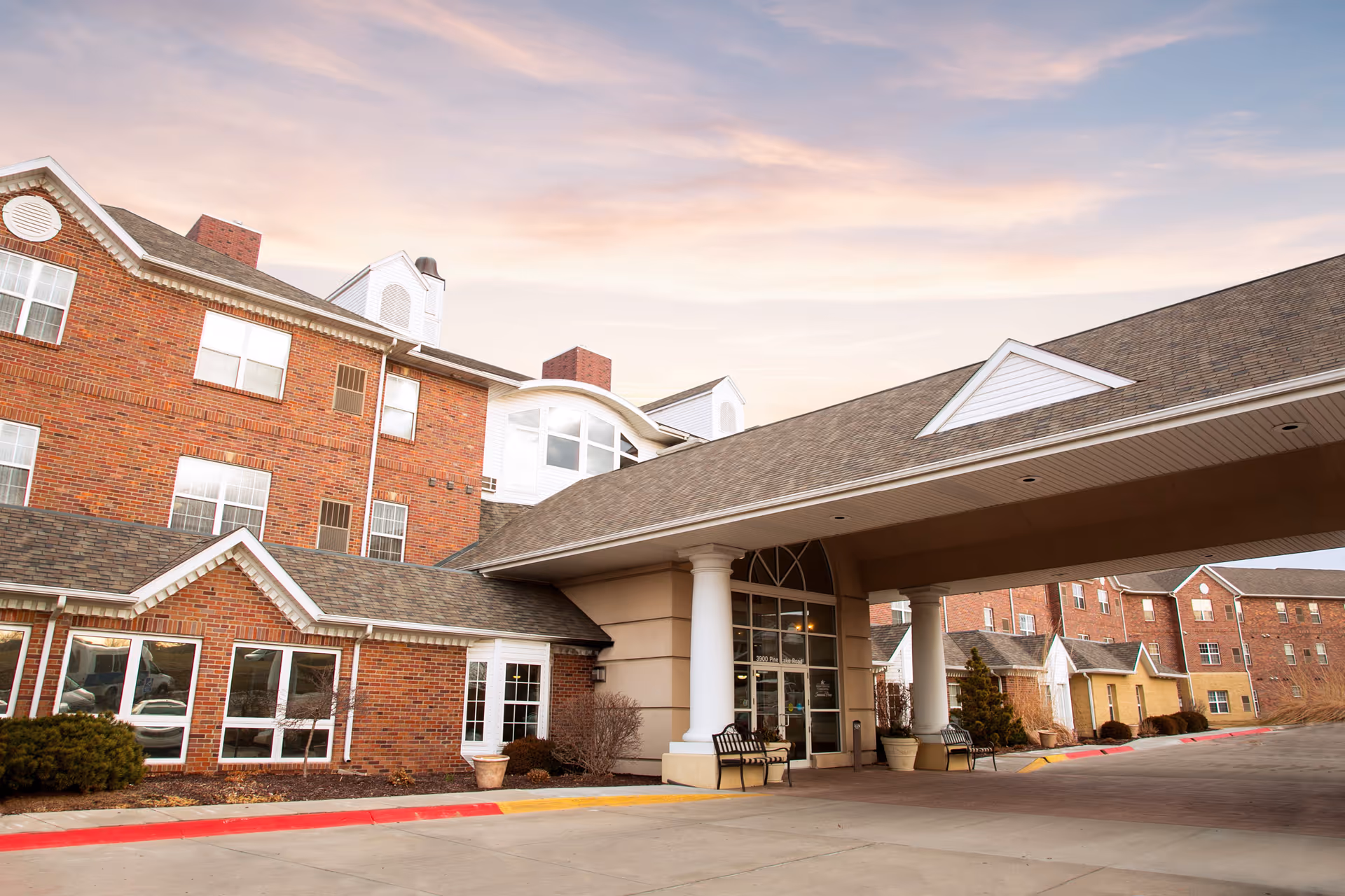 Exterior view of a brick Savannah Pines Retirement Community with a covered entrance.