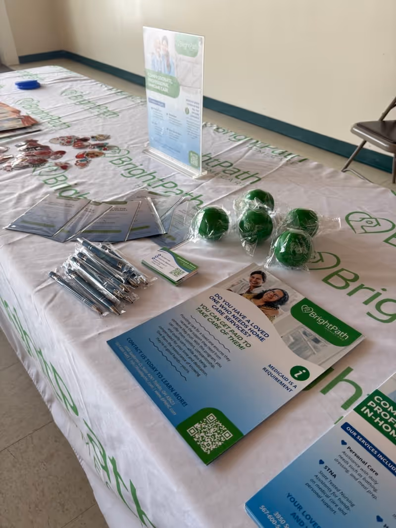 Indoor promotional table with Bright Path Home Care brochures and green stress balls.