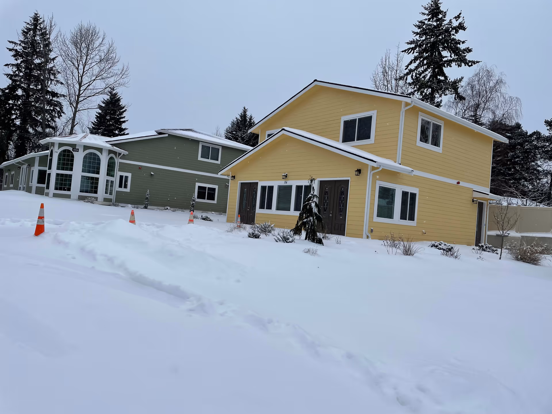 Two colorful, modern buildings sit in a snowy landscape with trees in the background.