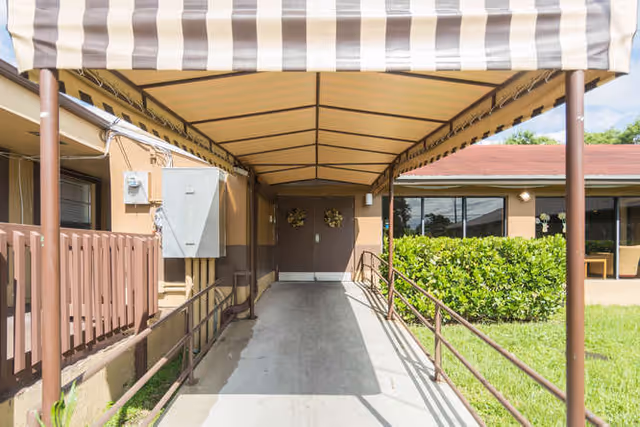 Entrance walkway to Colonial Assisted Living at Miami under a striped canopy.