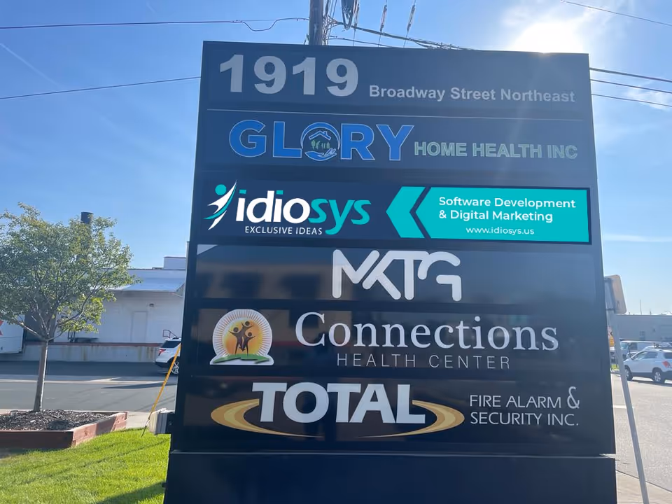 Tall outdoor signboard at 1919 Broadway Street Northeast displaying multiple company logos.