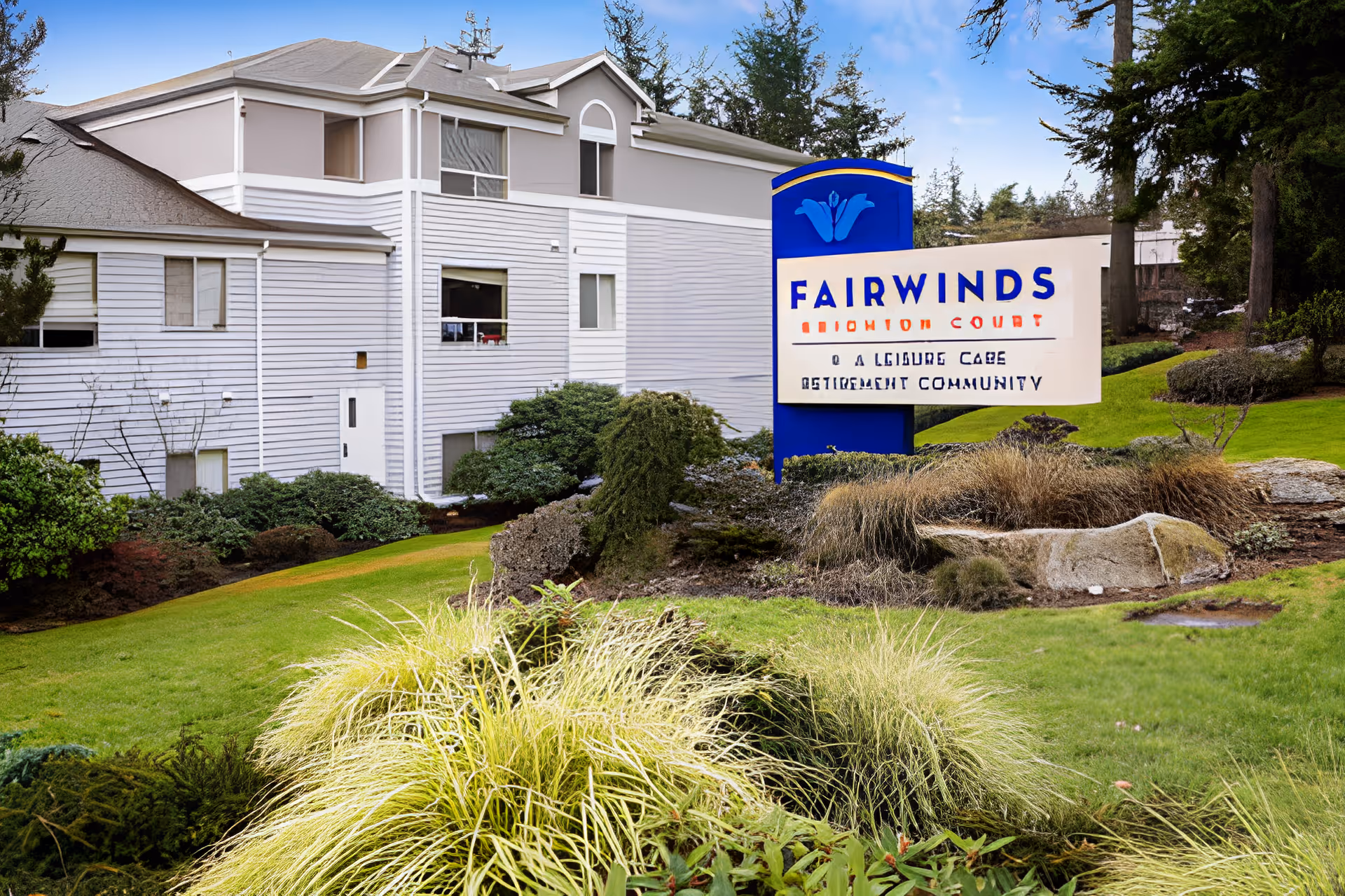 Exterior view of the Fairwinds Brighton Court retirement community building with landscaped grounds and a prominent blue entrance sign.