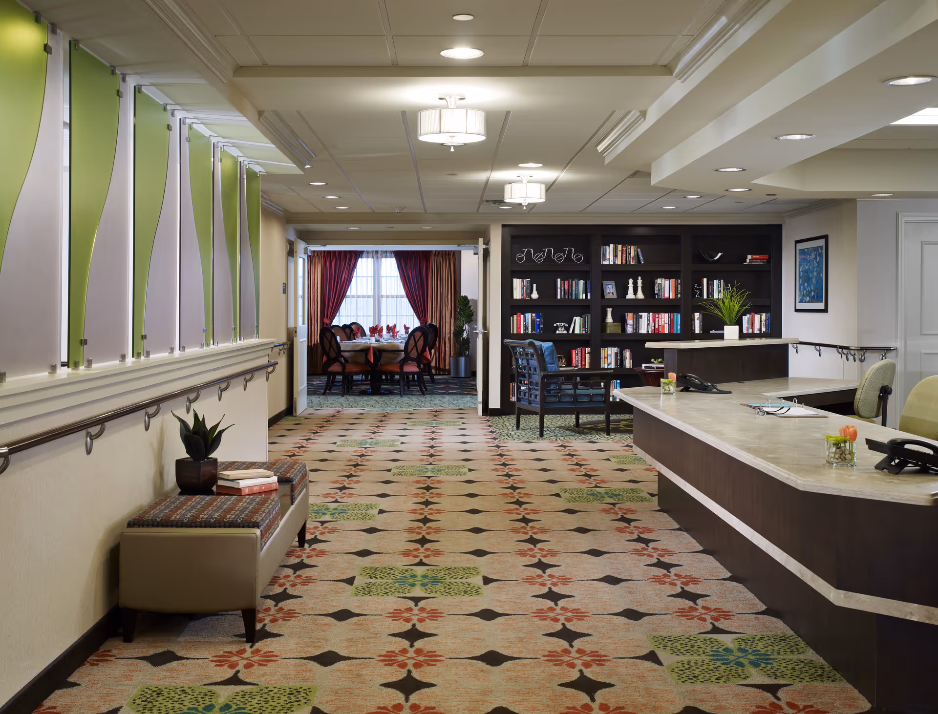 Lobby-style interior featuring a reception desk, library shelves, and seating.