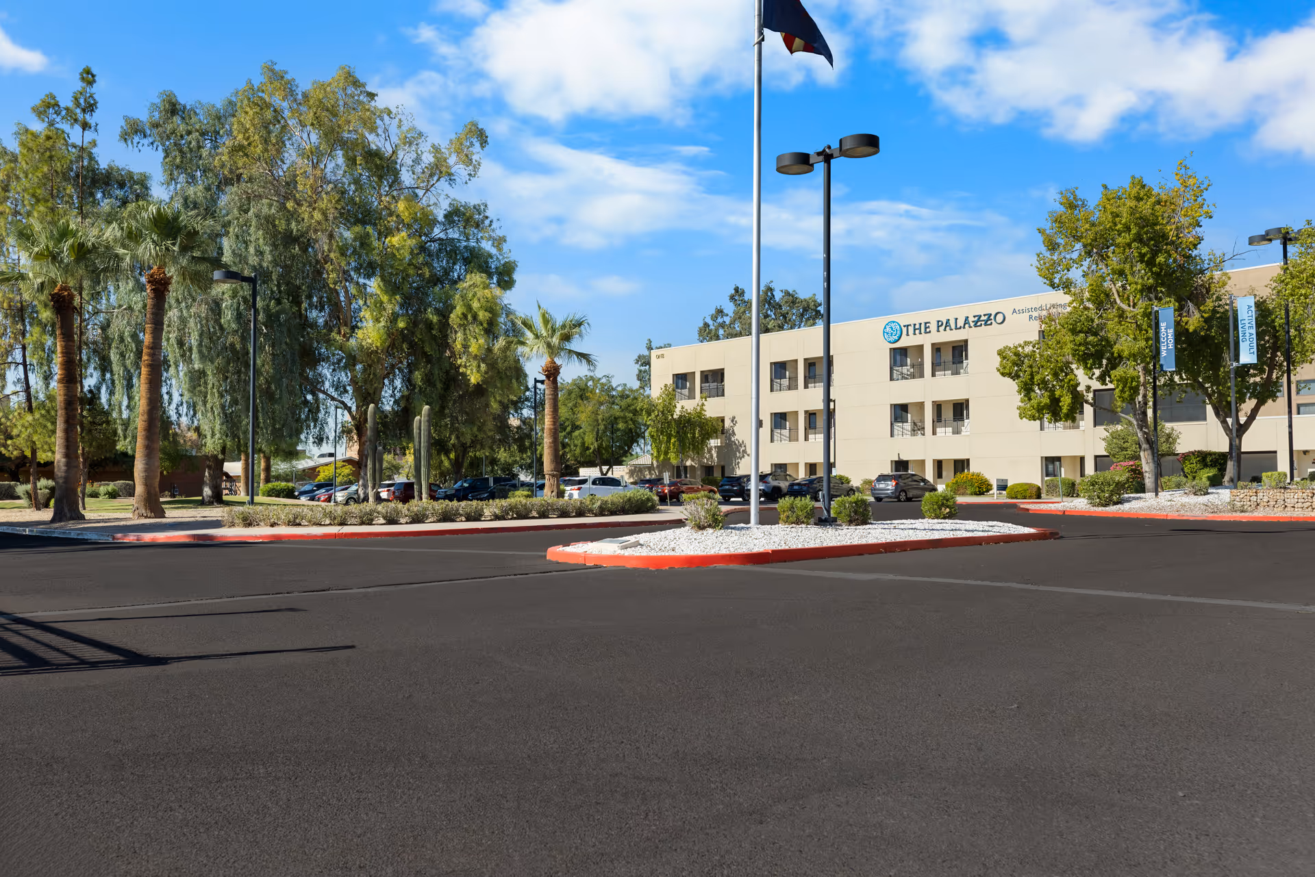 Exterior view of The Palazzo senior living facility with parking lot and palm trees.