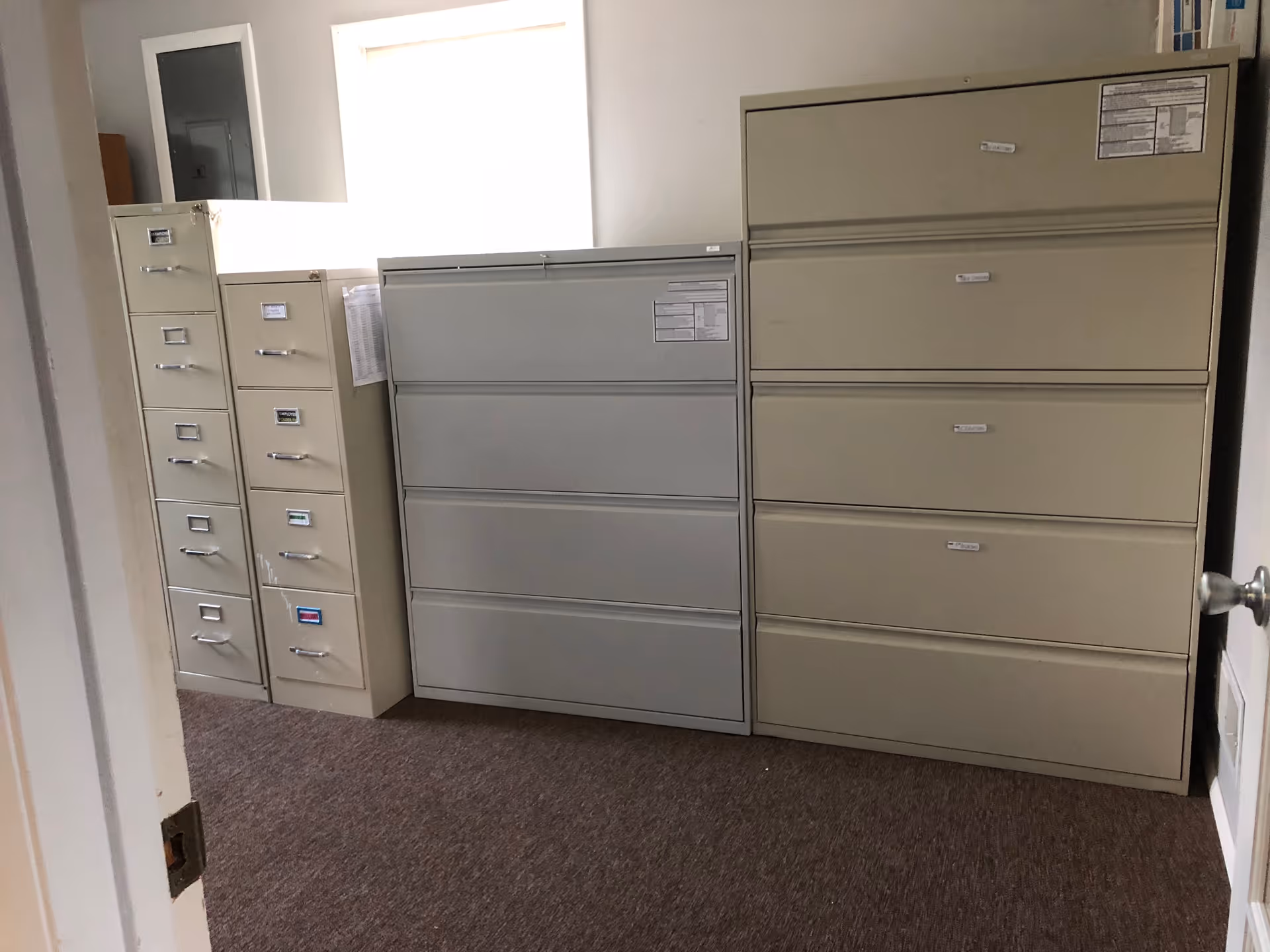 Tall metal filing cabinets line an office storage room against a plain wall.