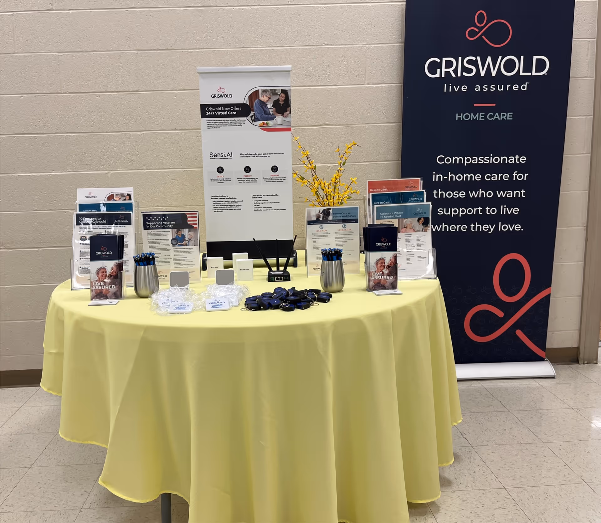 Information table with brochures and a tall Griswold banner inside a beige-walled hallway.