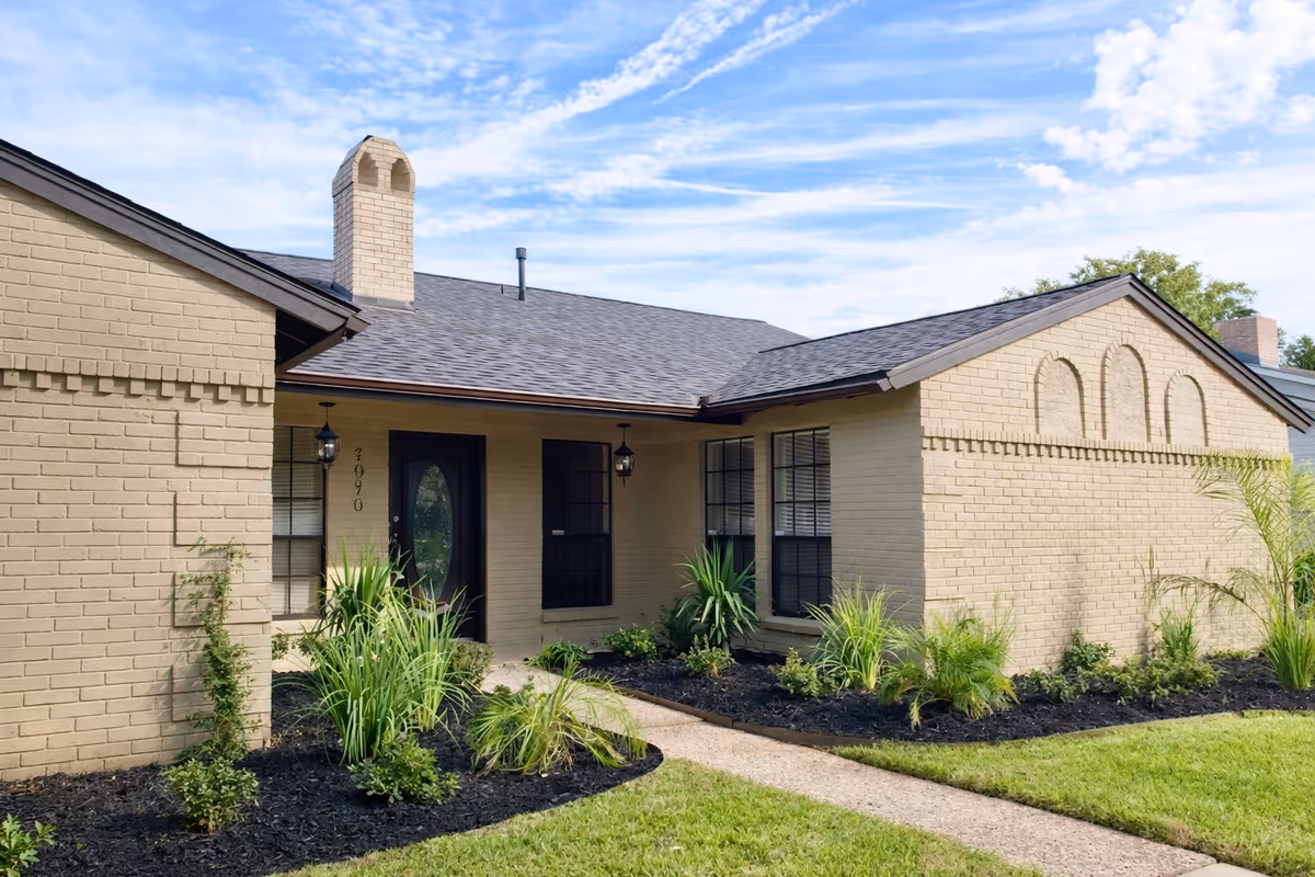 Single story beige brick assisted living facility with front entrance and landscaped walkway.