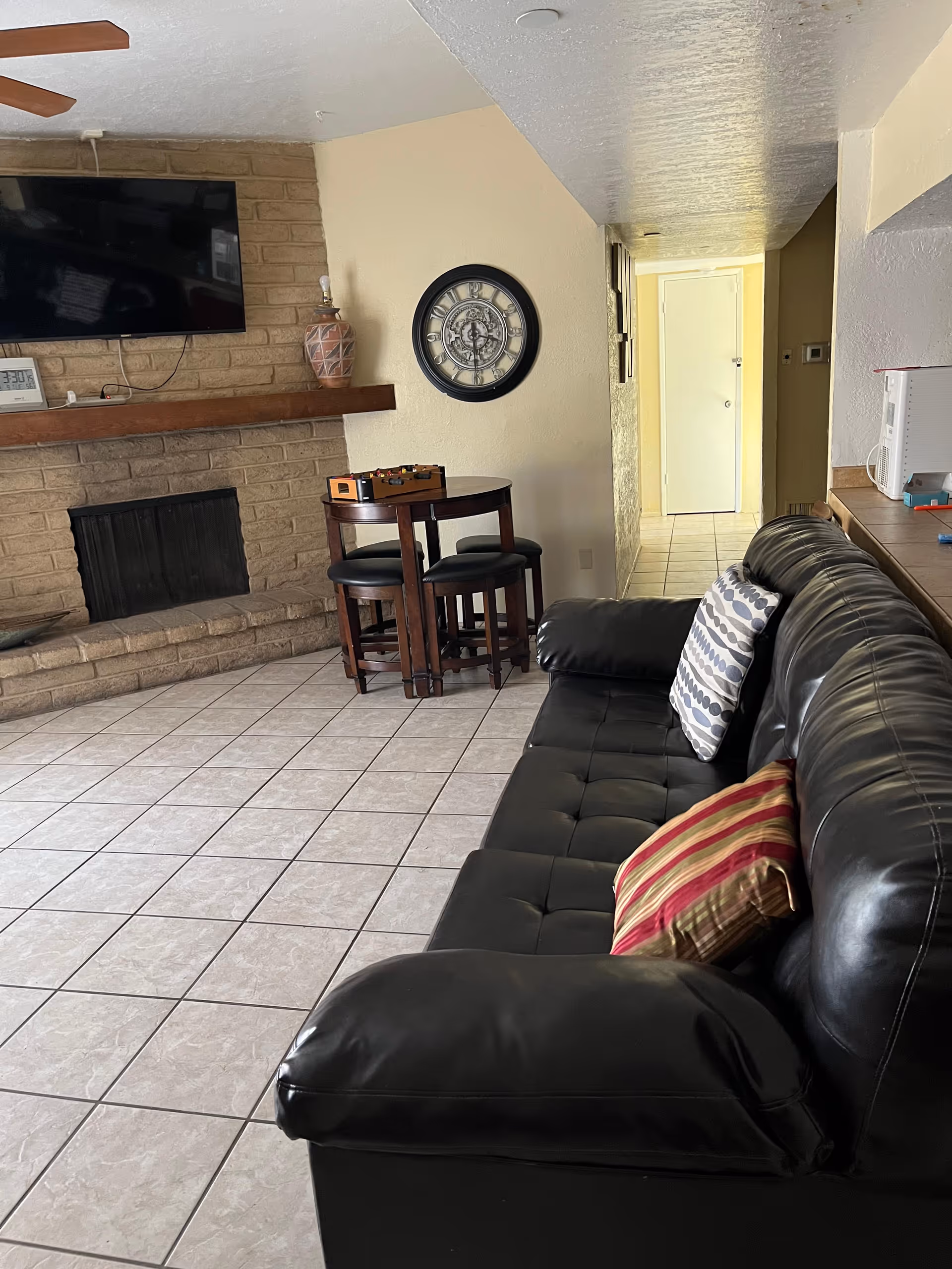Cozy living area with a leather sofa, fireplace, wall clock, and a small round table.