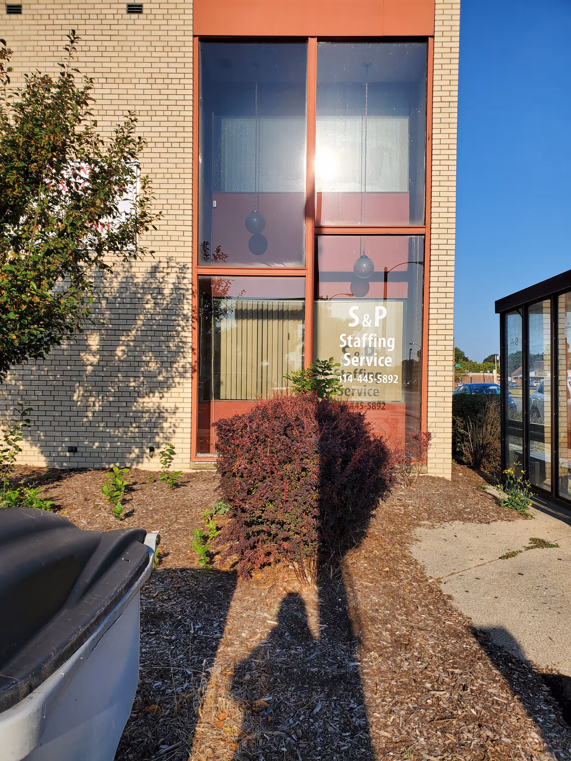 Front exterior of a brick building with large windows and S&P Staffing Service sign.