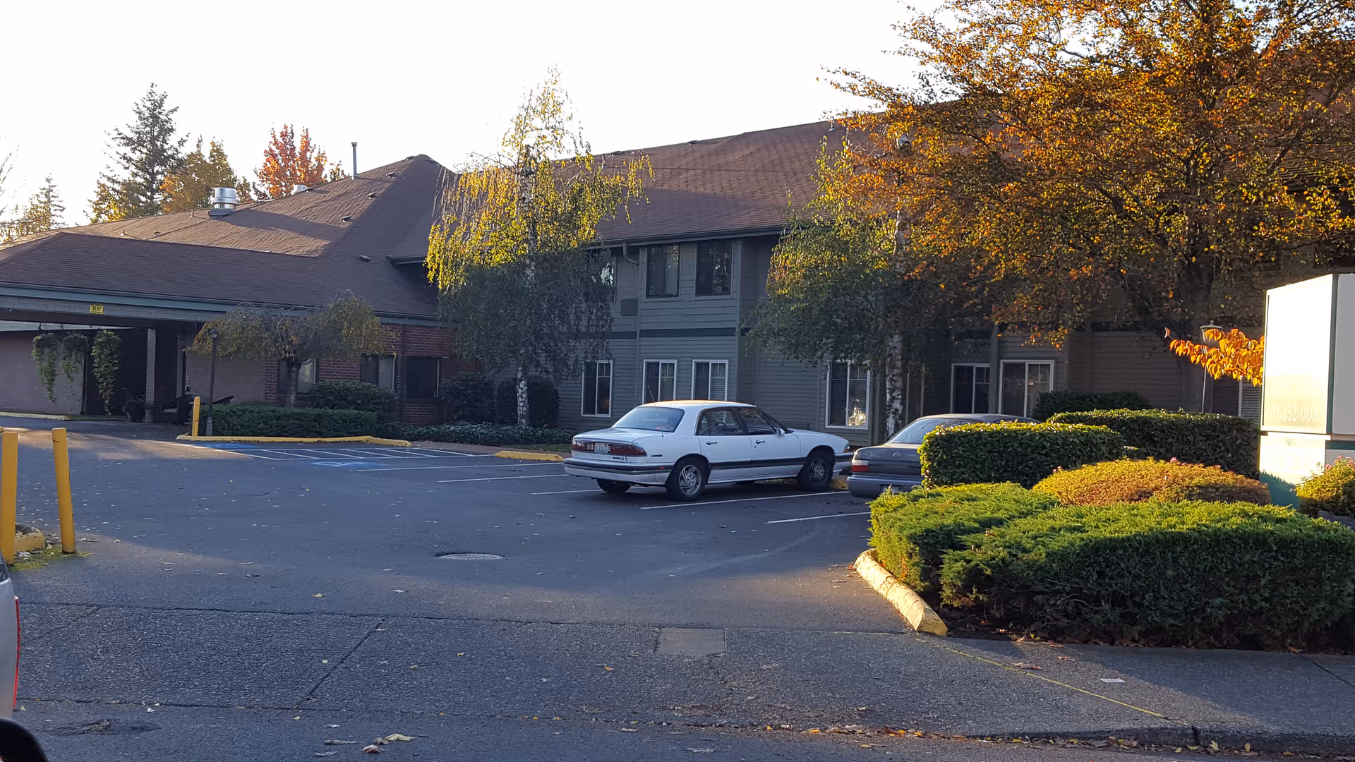 Exterior view of Firwood Gardens with parked cars and autumn trees.